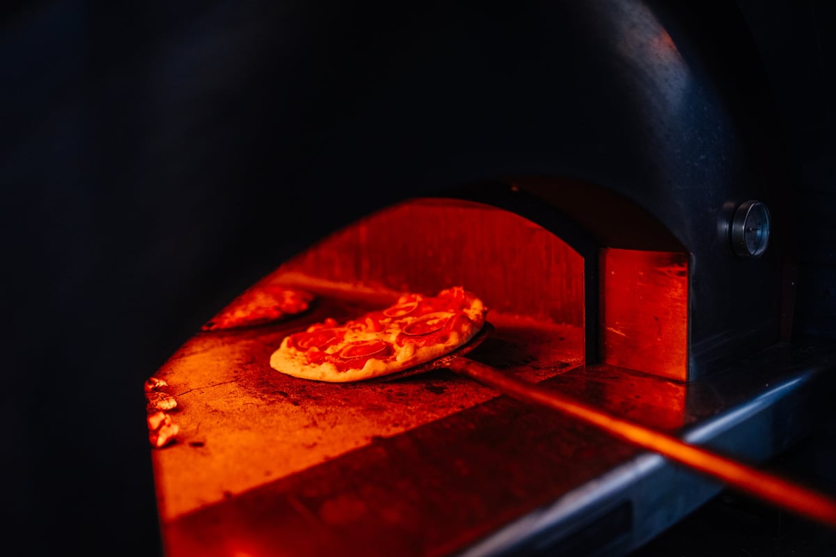 Pizza cotta nel forno a legna tradizionale, con fiamme e calore